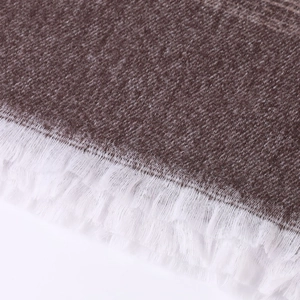 Close-up of brown knit texture with white fringe tassels on ethnic style shawl