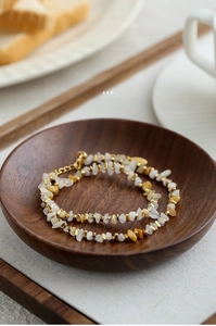 Detail of 18K gold plated brass necklace with irregular natural stone beads in a wooden bowl