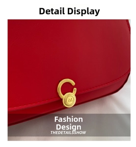 Detail einer runden goldenen Metallschnalle mit M-Gravur auf einer roten Ledertasche
