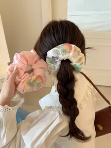 Detailed view of satin scrunchies with floral embroidery on pink and white fabric