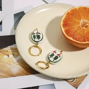 Dettaglio di orecchini d'oro con pendente mahjong in ceramica su piatto decorativo