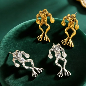 Vintage minimalist frog stud earrings in gold and silver finish on green velvet