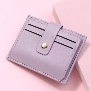 Close-up of lilac lychee grain leather card holder with gold circular metal buckle