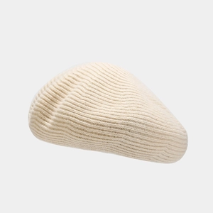 Detail of cream-white knitted wool beret showing thick spiral texture and warm fabric