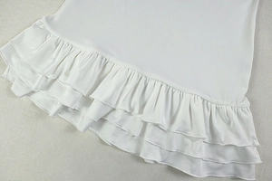 Detail view of the multi-layer pleated ruffles on a white sleeveless dress fabric