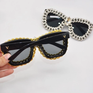 Close-up of cat-eye sunglasses featuring Cuban link chain temples and metal V logo