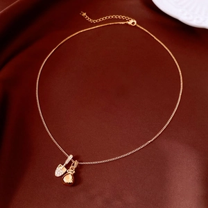 Macro detail of 18k gold plated teardrop pendant and pavé zircon spade on a silk fabric