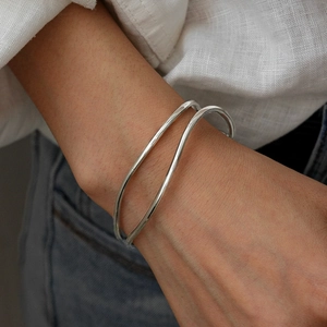 Minimalist silver wavy layered open bangle bracelet styled on woman's wrist