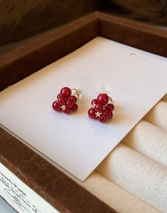 Macro detail of red resin cluster earrings with sparkling zircon centers on a gift box
