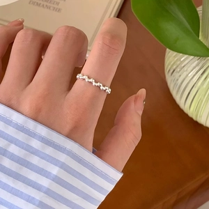 Detail of silver beaded ring on model finger in a cozy natural lifestyle setting