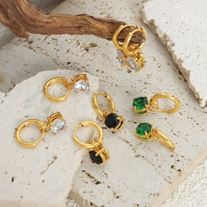 Eleganti orecchini in titanio dorato con zirconi colorati su sfondo di pietra naturale