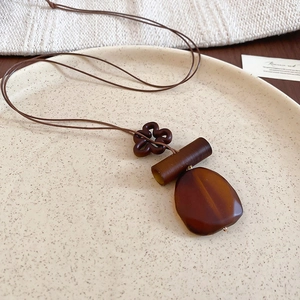 Detail of vintage resin heart pendant necklace on ceramic tray with aesthetic ethnic vibes
