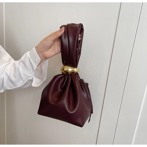 Detail of burgundy PU bucket bag featuring drawstring closure and gold metal handle ring