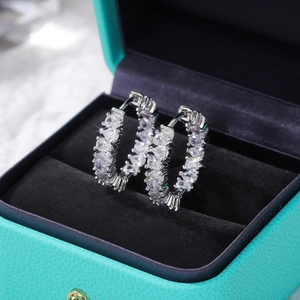 Detailed view of silver hoop earrings with pear-cut AAA zircons in a luxury jewelry box
