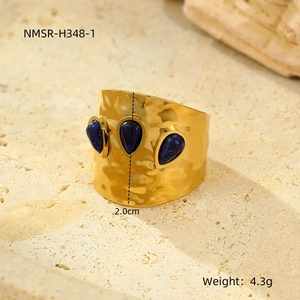 Macro detail of French vintage wide gold ring with pleated texture and three blue gemstones