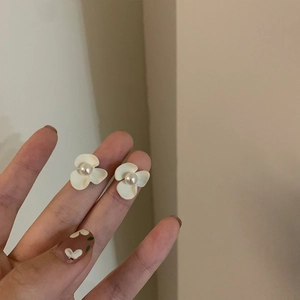 Gros plan de boucles d'oreilles fleurs blanches élégantes avec perles en main