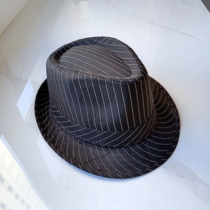 Close-up of black fedora hat with white pinstripes on marble surface at 45-degree angle