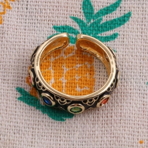 Detail of gold plated ring with colorful round stones and black enamel dripping oil