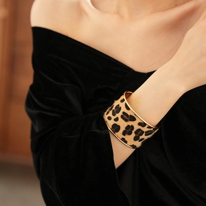 Close-up of leopard print velvet wide cuff bracelet with gold metal edges on a model's wrist