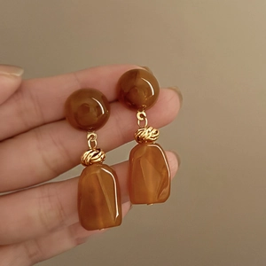 Detail of amber vintage drop earrings with marbled texture and golden metal twist