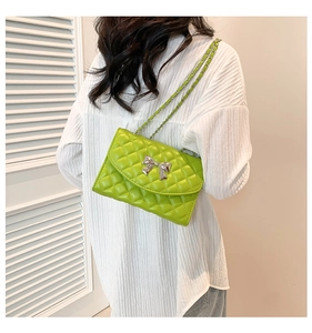Detail of lime green quilted handbag featuring a silver bow clasp and chain strap