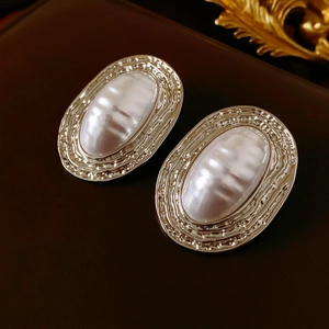 Detail of vintage oval earring with white pearl inlay and textured silver metal frame