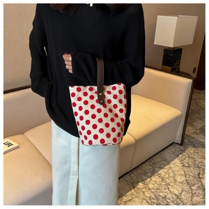 Polka dot canvas bucket bag with brown leather handles held by a model in a cozy room
