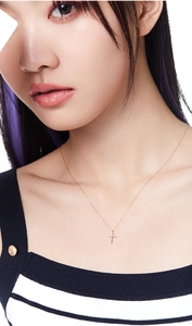 Close-up of a 925 sterling silver cross necklace with pavé crystals on a female model
