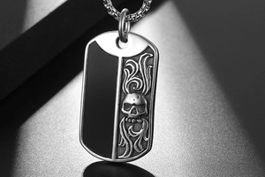 Detailed close-up of dual-color titanium steel military tag with skull and flame motifs