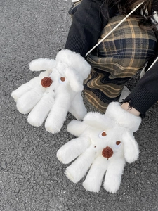 Detail of white plush cartoon dog gloves with embroidery and brown pom-pom nose