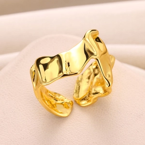 Macro shot of irregular molten lava textured gold plated wide open ring with metallic luster