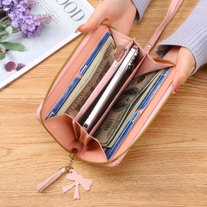 Pink long zip-around wallet with tassels, bow decor and multi-slot interior for smartphone