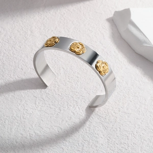 Silver-toned C-shaped titanium steel bracelet with three gold 3D floral accents