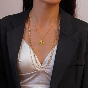 Detail of layered 18K gold plated stainless steel sun coin and pearl necklaces