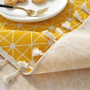 Close-up of yellow and beige geometric cotton linen tablecloth with fringe edges