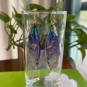 Detail of blue purple gradient cicada wing earrings with gold foil and translucent texture