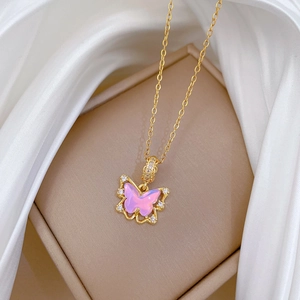 Gros plan du pendentif papillon en opale rose avec chaîne dorée sur fond de soie