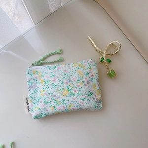 Détail d'un porte-monnaie floral en coton avec fermeture éclair et poignée tissée verte