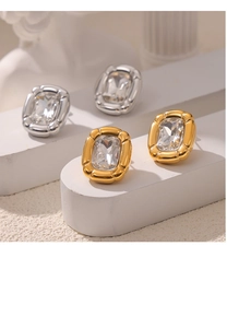 Detail of gold and silver titanium earrings with large crystals on a white pedestal