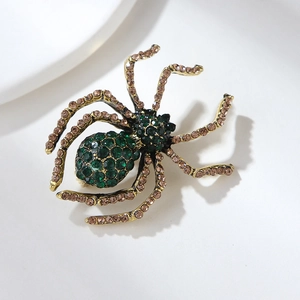 Macro shot of spider brooch with green rhinestones and brown crystals on metal legs