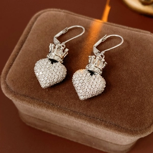 Gros plan de boucles d'oreilles cœur en argent scintillant avec détail de couronne