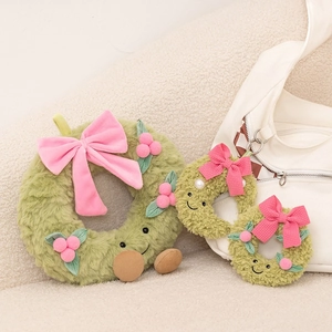 Detailed view of green plush Christmas wreaths with pink bows on a cozy sofa setting