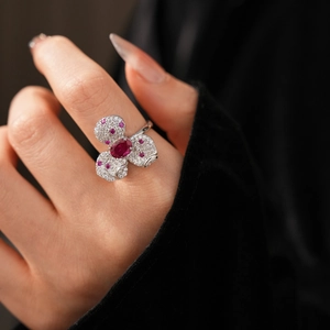 Close-up of vintage flower ring with red gemstone and white diamonds on model's finger