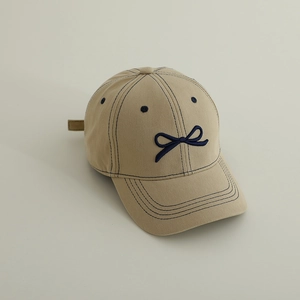 Détail du nœud brodé et des œillets d'aération sur la casquette en coton beige