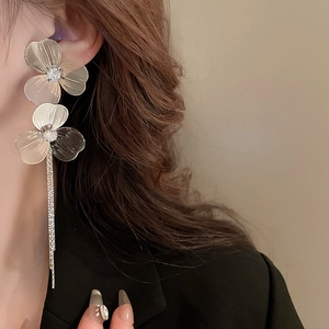 Détail de boucles d'oreilles fleurs plaquées or à longs glands avec strass sur mannequin