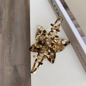 Macro detail of tortoiseshell acetate hair claw clip with vintage bow design on white desk
