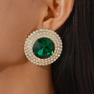 Close-up of luxury halo stud earring with green crystal and gold finish on model