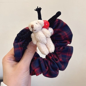 Close-up of plaid scrunchie with cute plush bear and festive decorative charms