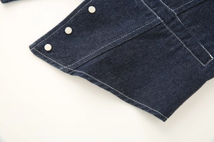 Detailed macro view of dark blue denim fabric with silver studs and white stitching