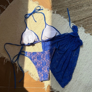 Close-up of royal blue floral lace fabric on a three-piece bikini set and beach skirt